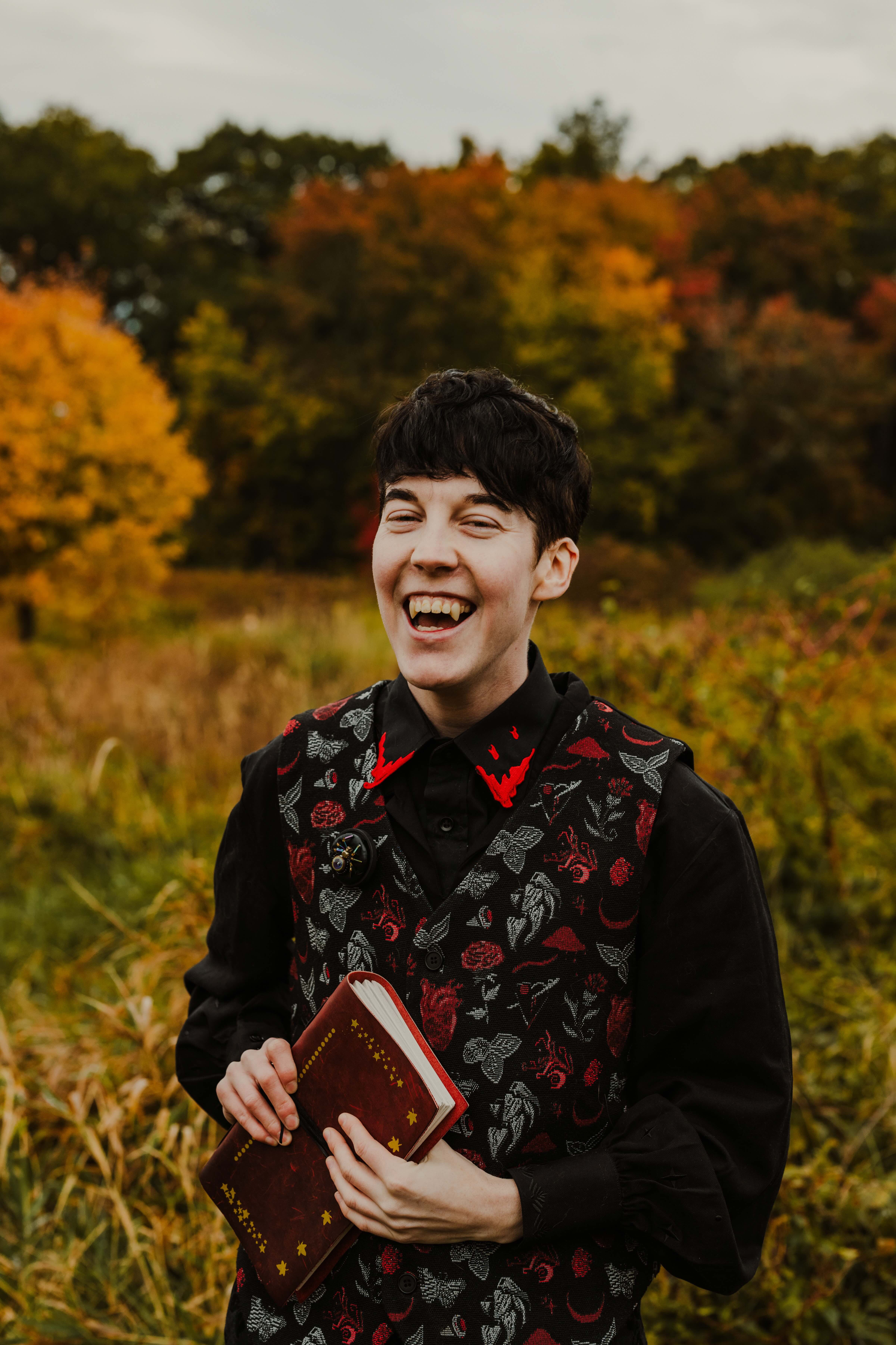 Picture of Fin Leary: person with short dark hair, laughing, and holding a book